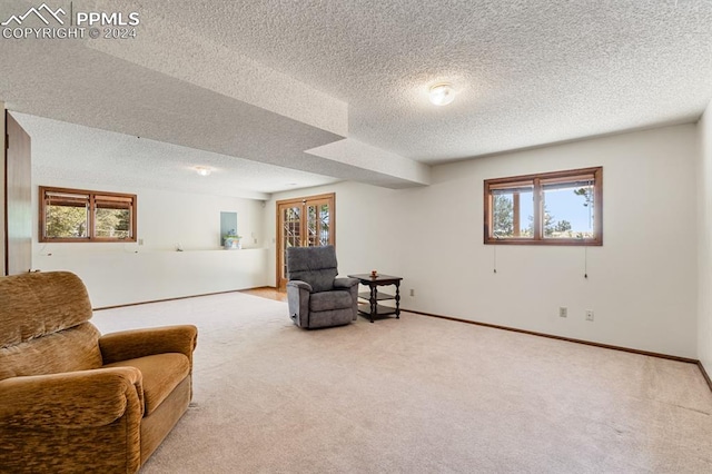 sitting room featuring a healthy amount of sunlight, a textured ceiling, and light carpet