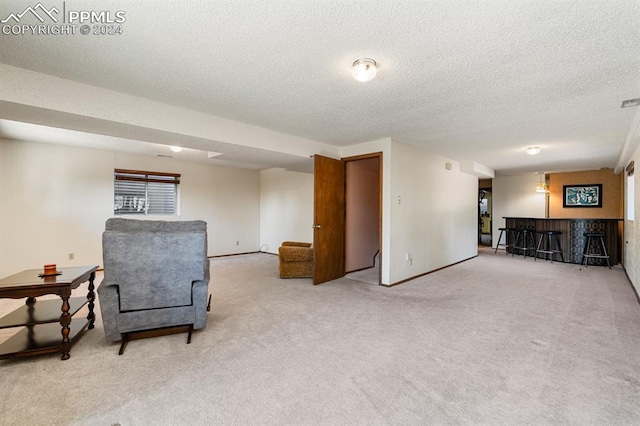 living area featuring bar area, carpet floors, and a textured ceiling