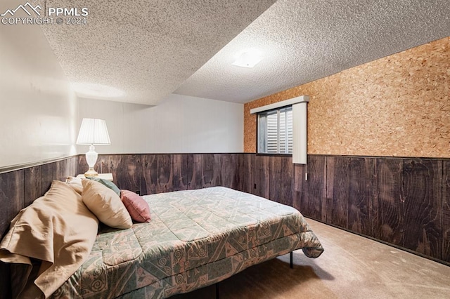 bedroom featuring wood walls, carpet floors, and a textured ceiling