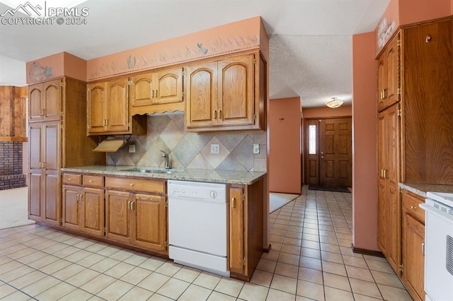 kitchen with decorative backsplash, stove, sink, light tile patterned floors, and dishwasher