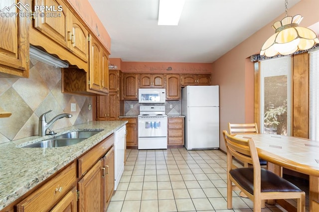 kitchen featuring light stone countertops, sink, white appliances, decorative backsplash, and light tile patterned floors