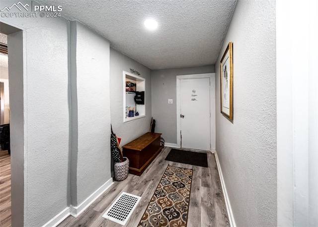 doorway to outside with a textured ceiling and light hardwood / wood-style floors