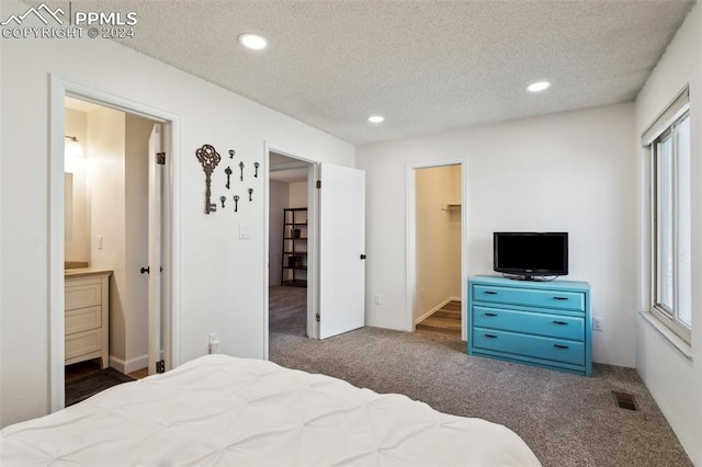 bedroom featuring dark carpet, a spacious closet, a textured ceiling, connected bathroom, and a closet