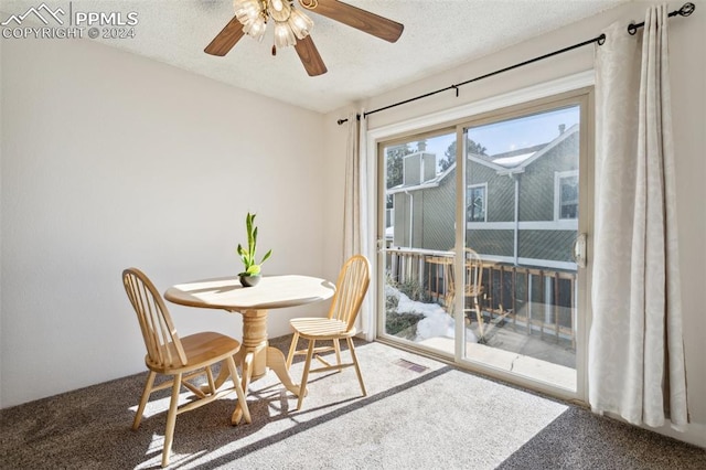 carpeted dining area with a textured ceiling and ceiling fan