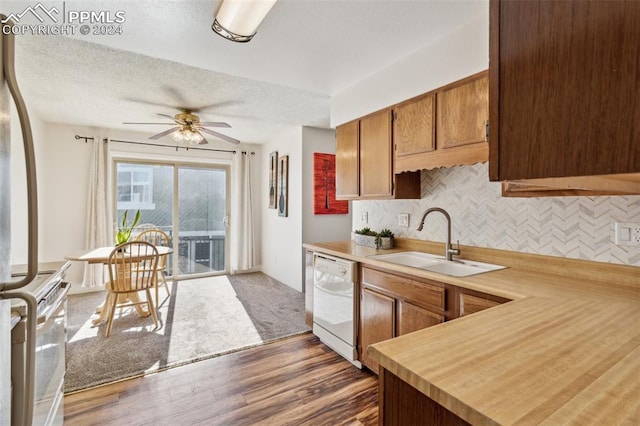 kitchen with white appliances, backsplash, sink, a textured ceiling, and dark hardwood / wood-style flooring