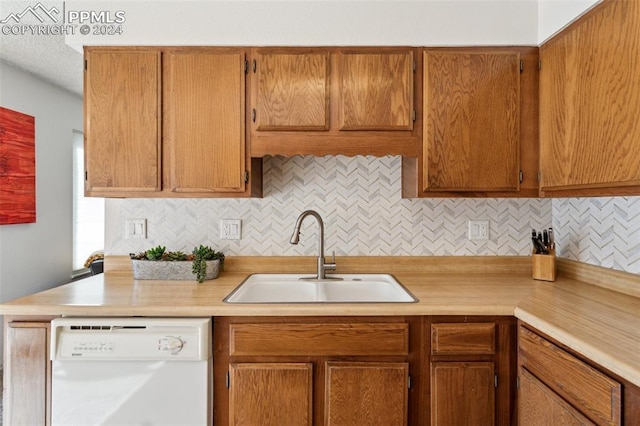 kitchen featuring decorative backsplash, sink, and white dishwasher