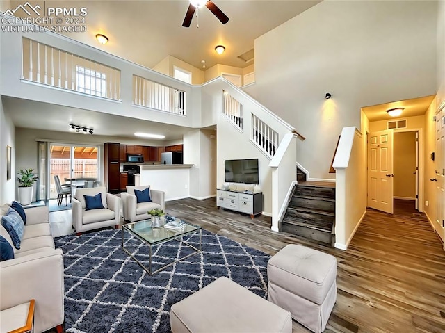 living room featuring a high ceiling, dark hardwood / wood-style floors, and ceiling fan