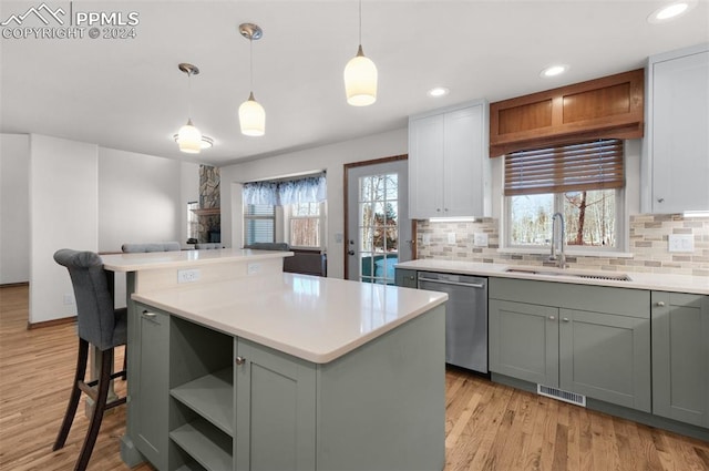 kitchen featuring dishwasher, white cabinets, a kitchen island, and hanging light fixtures