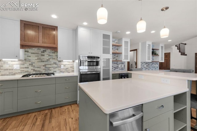 kitchen featuring light hardwood / wood-style flooring, white cabinets, hanging light fixtures, and appliances with stainless steel finishes