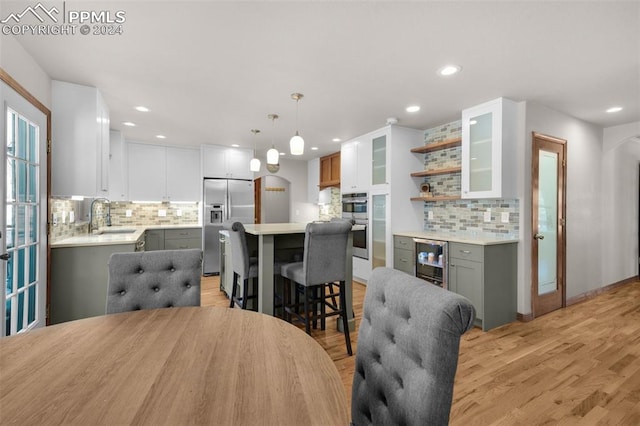 kitchen featuring appliances with stainless steel finishes, light hardwood / wood-style flooring, beverage cooler, and gray cabinetry