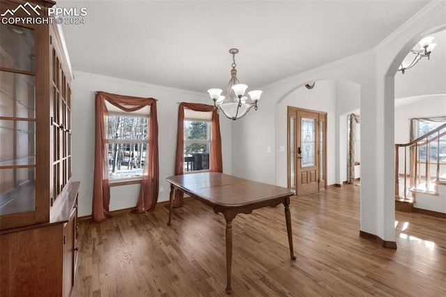 unfurnished dining area featuring wood-type flooring, an inviting chandelier, and crown molding