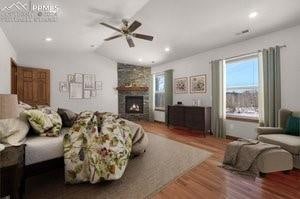 bedroom featuring ceiling fan, a fireplace, wood-type flooring, and lofted ceiling