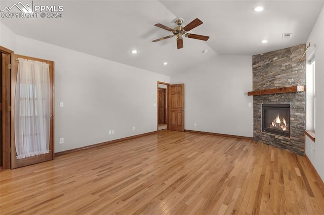 unfurnished living room with light wood-type flooring, vaulted ceiling, ceiling fan, and a stone fireplace