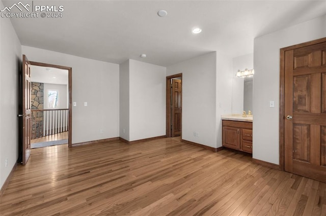 unfurnished bedroom featuring light hardwood / wood-style floors and ensuite bath