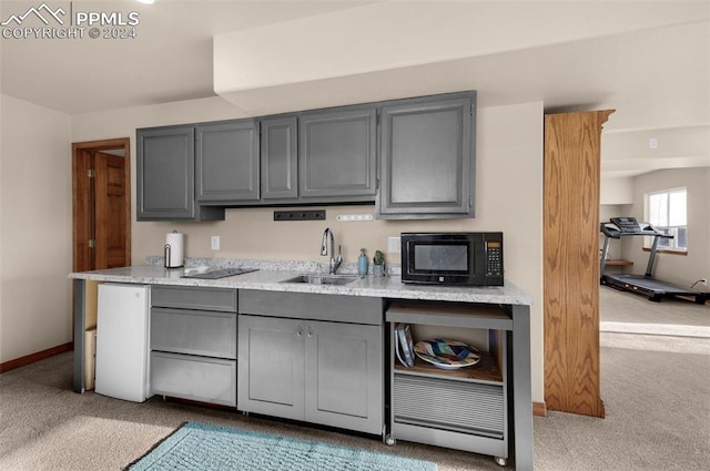 kitchen with gray cabinetry, light carpet, and sink