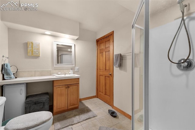 bathroom with toilet, vanity, tile patterned floors, and a shower with door