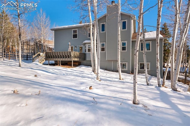 snow covered house with a wooden deck