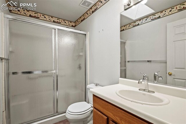 bathroom featuring vanity, a skylight, toilet, and walk in shower