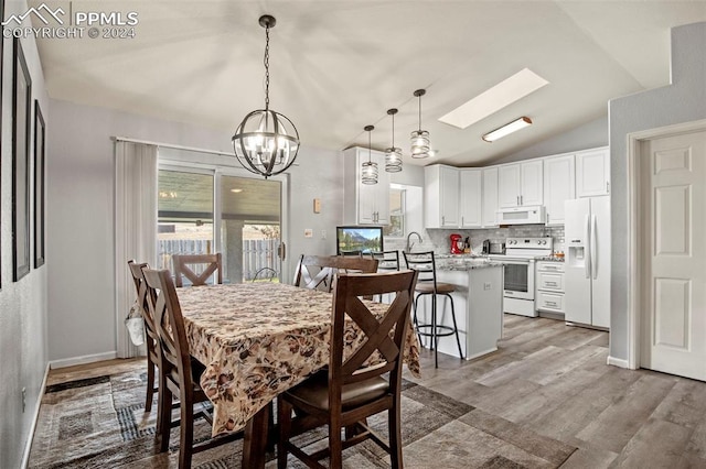 dining space with a chandelier, hardwood / wood-style floors, lofted ceiling with skylight, and sink