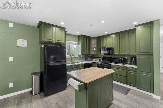 kitchen featuring sink, light wood-type flooring, wooden counters, and black appliances