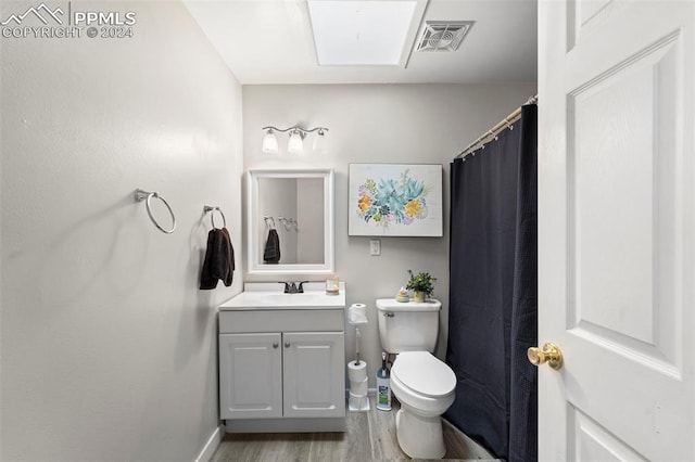 bathroom featuring hardwood / wood-style floors, vanity, a skylight, and toilet