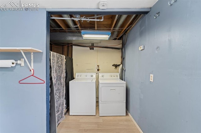 laundry room featuring separate washer and dryer and light hardwood / wood-style flooring