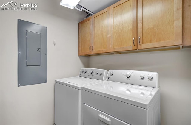 washroom with cabinets, washing machine and dryer, and electric panel