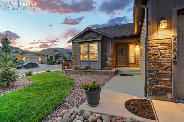 exterior entry at dusk featuring a yard