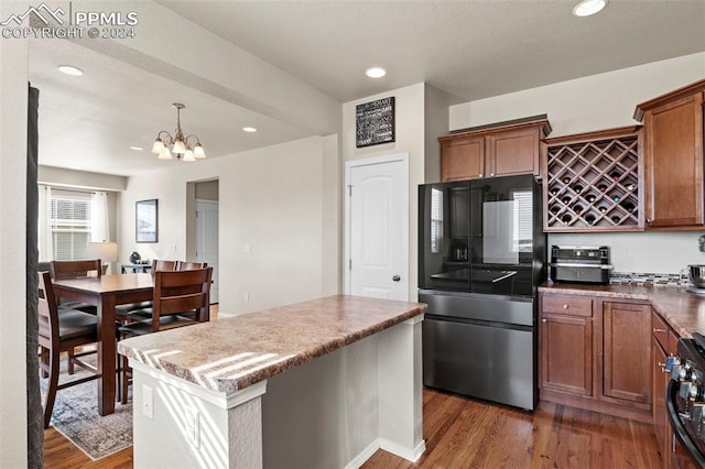 kitchen featuring an inviting chandelier, dark hardwood / wood-style floors, decorative light fixtures, a kitchen island, and black appliances