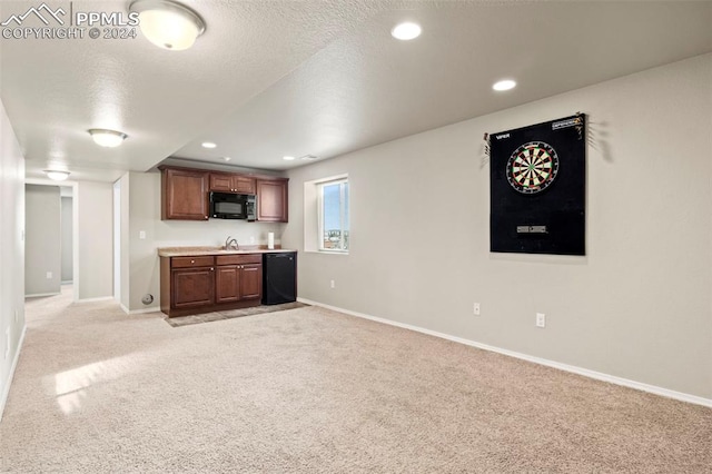 interior space featuring sink, light colored carpet, black appliances, and a textured ceiling