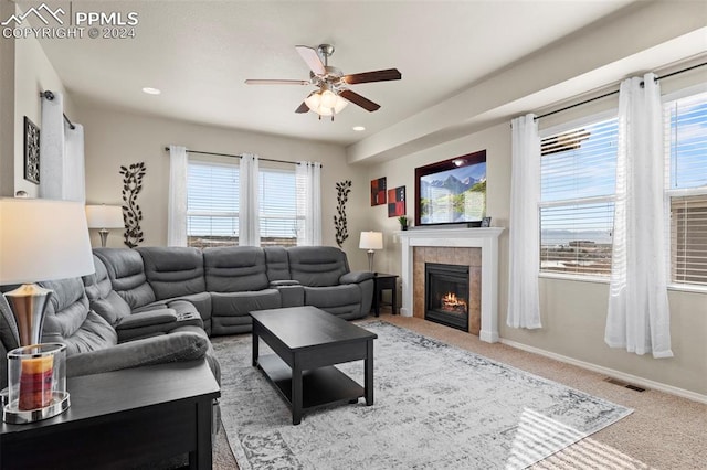 living room featuring a tiled fireplace, ceiling fan, plenty of natural light, and carpet