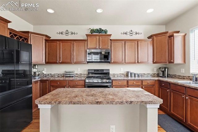 kitchen with sink, a kitchen island, stainless steel appliances, and light hardwood / wood-style floors