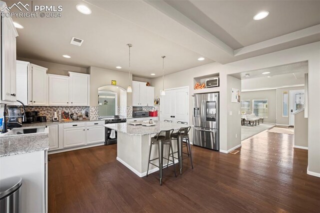 kitchen with a center island, dark hardwood / wood-style flooring, decorative light fixtures, white cabinets, and appliances with stainless steel finishes