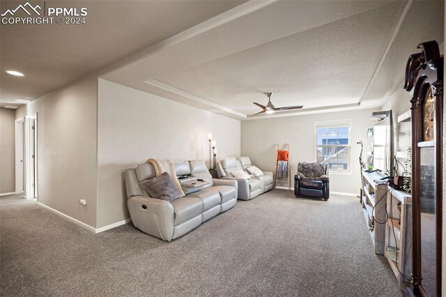 carpeted living room with a tray ceiling and ceiling fan