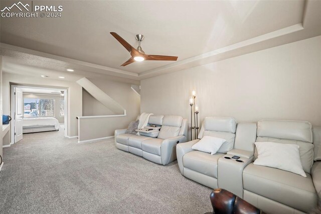 living room with ceiling fan, carpet floors, and a tray ceiling