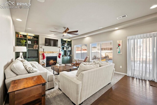 living room with hardwood / wood-style flooring, a stone fireplace, and ceiling fan