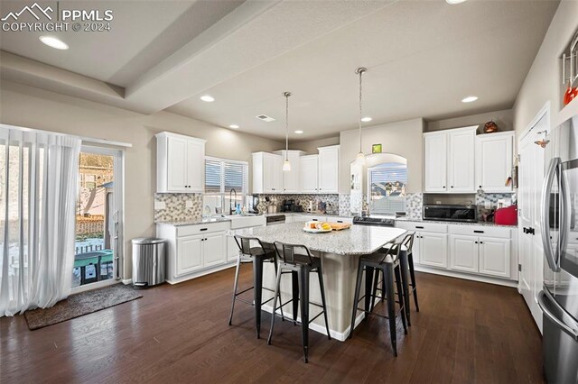 kitchen featuring dark hardwood / wood-style flooring, white cabinetry, a center island, and decorative light fixtures