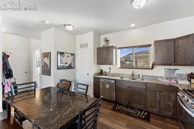 kitchen featuring a center island, sink, dark stone countertops, appliances with stainless steel finishes, and dark hardwood / wood-style flooring