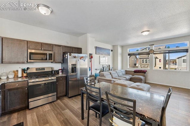 kitchen featuring dark brown cabinetry, stainless steel appliances, a textured ceiling, and wood-type flooring