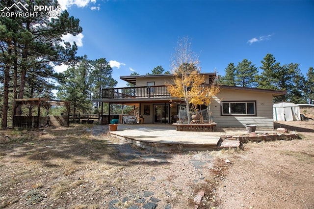 rear view of house featuring a storage unit, a patio area, and a deck