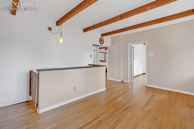 spare room with beamed ceiling and light hardwood / wood-style flooring