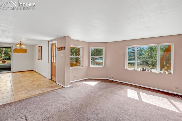 carpeted empty room featuring a chandelier