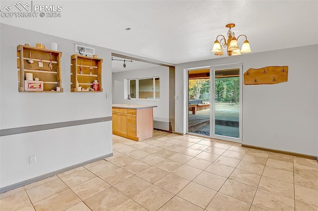 interior space with light tile patterned flooring, light brown cabinetry, and a chandelier