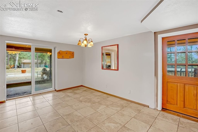 unfurnished room featuring light tile patterned floors, a healthy amount of sunlight, and an inviting chandelier