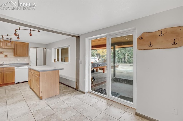 kitchen featuring light brown cabinetry, tasteful backsplash, white dishwasher, sink, and a center island