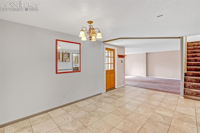 empty room featuring light colored carpet and a notable chandelier