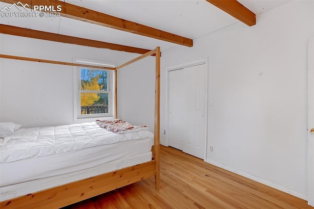 bedroom with beamed ceiling and hardwood / wood-style floors