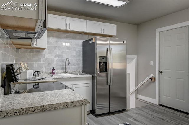 kitchen with backsplash, white cabinets, sink, appliances with stainless steel finishes, and light hardwood / wood-style floors