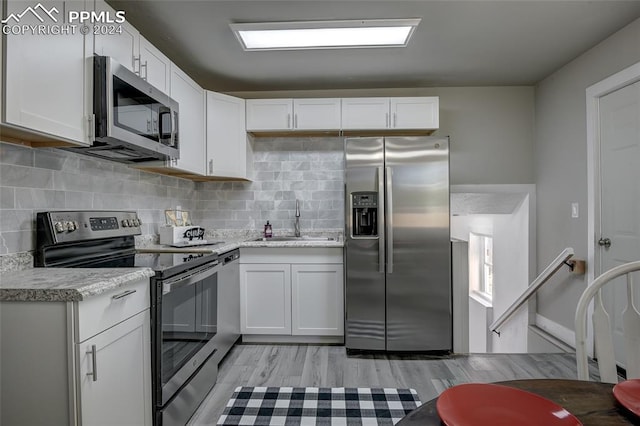 kitchen with sink, white cabinetry, stainless steel appliances, and light wood-type flooring