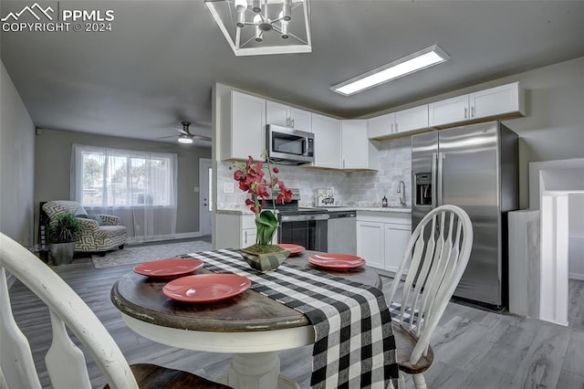 dining space with ceiling fan with notable chandelier, light hardwood / wood-style floors, and sink